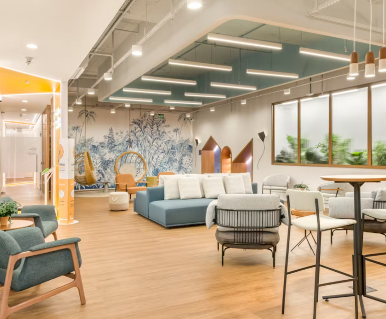 Sala de espera decorada com papel de parede estampado azul, sofás,cadeiras e puffs azul e off white, piso laminado claro, ambiente bem iluminado