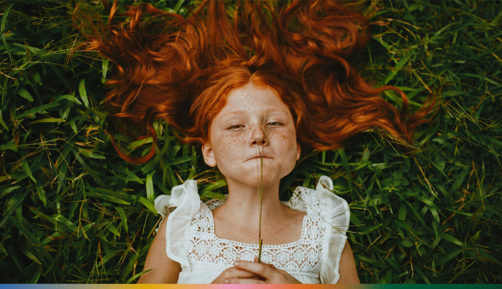 Criança ruiva na grama